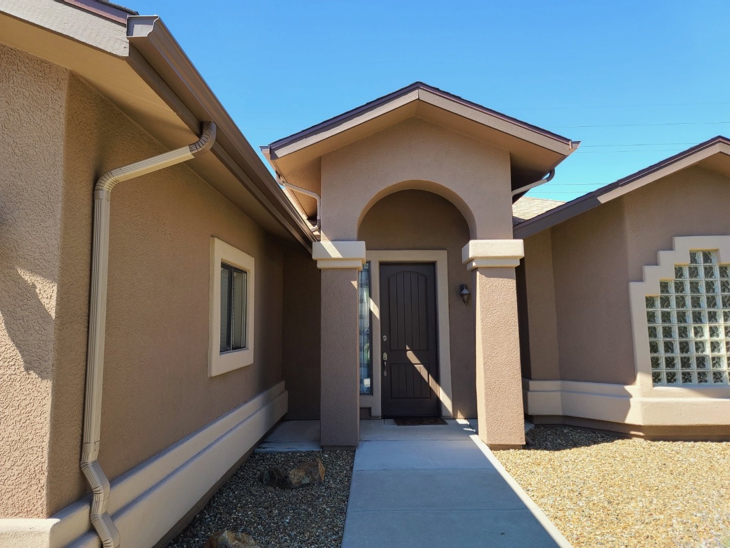 Gutter and downspout details beside a stucco entryway